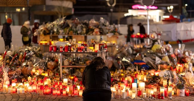 A woman lights a candle at a makeshift memorial outside the "Le Constellation" bar, after a deadly fire and explosion during a New Year's Eve party, in the upscale ski resort of Crans-Montana in southwestern Switzerland, January 5, 2026. REUTERS/Umit Bektas