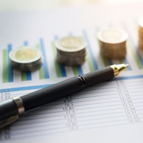 financial charts on the table with laptop, calculator, pen and glasses business concept.