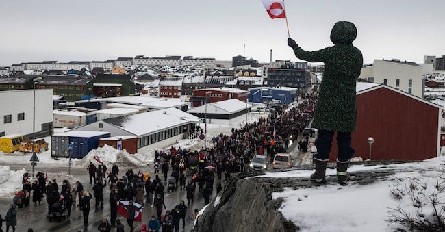 Una donna sventola una bandiera groenlandese mentre la gente partecipa a una manifestazione contro la richiesta del presidente degli Stati Uniti Donald Trump di cedere l'isola artica agli Stati Uniti, chiedendo che le sia permesso di determinare il proprio futuro, a Nuuk, Groenlandia, il 17 gennaio 2026. REUTERS/Marko Djurica