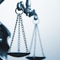 Close up detail of the scales of justice being held aloft by a small statue of Justice over a grey background with copy space conceptual of law and order