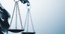 Close up detail of the scales of justice being held aloft by a small statue of Justice over a grey background with copy space conceptual of law and order