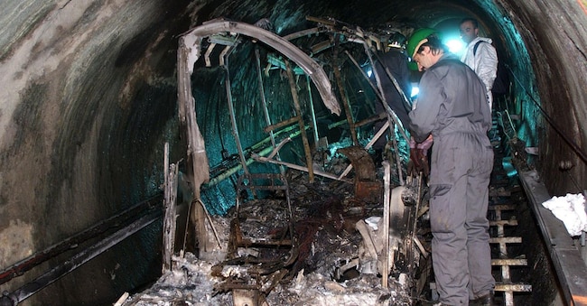 Soccorritori non identificati osservano i resti carbonizzati della funicolare nel tunnel della stazione sciistica del ghiacciaio Kitzsteinhorn in Austria. (Ansa/Franz Neumayr)