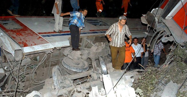 La gente osserva i detriti del vagone ribaltato in seguito al deragliamento avvenuto giovedì 22 luglio 2004 nei pressi di Pamukova, a Sakarya. (Ansa - Halil Ibrahim Uyar)