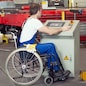 disabled worker in wheelchair in factory on the machine
