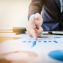 Working process startup. Businessman working with new finance project at office with laptop, tablet and graph data documents on his desk