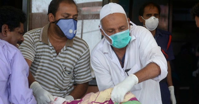 Foto d’archivio - Gli assistenti indossano maschere come misura precauzionale contro il virus Nipah mentre aiutano un paziente all'ospedale Government Medical College di Kozhikode, nello stato meridionale indiano del Kerala, nel precedente focolaio del 2018  (Foto AP)