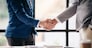 Two men shake hands in a business meeting. Scene is professional and formal. The handshake symbolizes agreement and trust between the two men