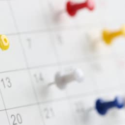 Various color thumb tack pins on calendar as reminder. Important business days concept