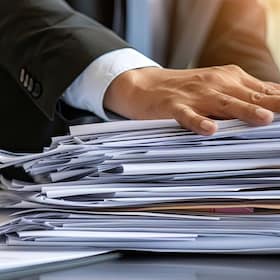 A businessman with a bundle of paper documents in hand.