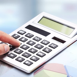 Hand with calculator over blue office background. Accounting.