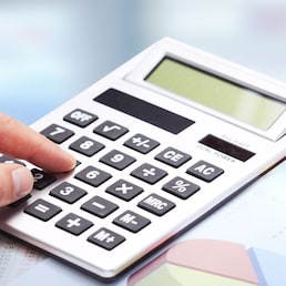 Hand with calculator over blue office background. Accounting.