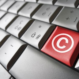 Digital copyright web content and Internet concept with copyright symbol and icon on a red laptop computer key for blog, website and online business.