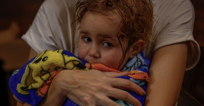 Yuliia Davydenko, 40 anni, tiene in braccio sua figlia Stephanie, 2 anni, avvolta in un asciugamano dopo aver fatto la doccia in un bagno pubblico, poiché il loro appartamento non ha riscaldamento né acqua calda e subisce frequenti interruzioni di corrente a causa dell'attacco della Russia all'Ucraina. REUTERS/Alina Smutko 