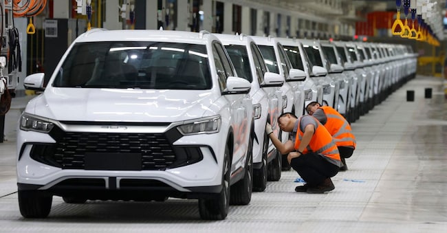 Le persone puliscono i veicoli durante l'inaugurazione dello stabilimento dell'azienda cinese Build Your Dreams (BYD), che fungerà da base per l'azienda. (EPA)
