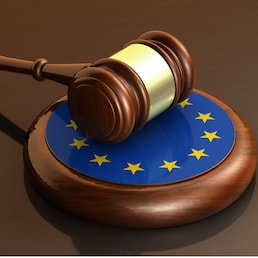 European Union laws, legal system and parliament concept with a 3d render of a gavel on a wooden desktop and the EU flag.