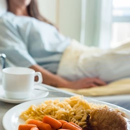 Food delivered to a patient in hospital bed, focus on the meal