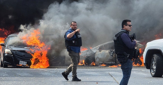 Gli agenti messicani di polizia mettono in sicurezza un’area dove alcuni veicoli sono stati incendiati dai membri della criminalità organizzata per bloccare una strada, in seguito all’operazione militare in cui è stato ucciso il capo dei narcos “El Mencho” (Reuters)