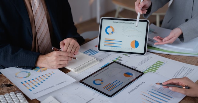 Business team analyzing financial documents, charts and graphs using digital tablets during a meeting to discuss company's performance and sales using data visualization tools
