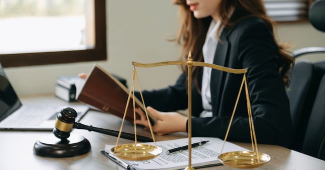 Woman lawyer in the office with brass scale on wooden table. justice and law concept in morning light