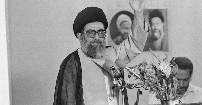 Il leader supremo iraniano Ali Khamenei saluta la folla durante la preghiera del venerdì, con un fucile automatico visibile dietro il podio, a Teheran, Iran. 17 luglio 1989 REUTERS/Fatih Saribas/Foto d'archivio