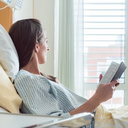 Patient in hospital room looking out of the window from bed hoping for quick recovery