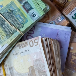 Bundles of European banknotes tied with rubber bands.