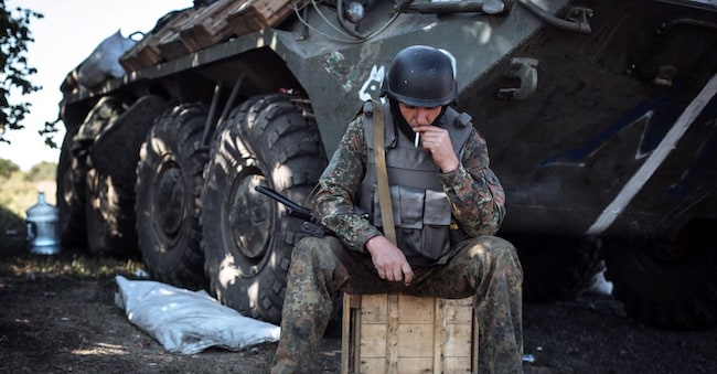 Un soldato ucraino fuma mentre riposa a un posto di blocco vicino alla città di Debalcevo, nell'Ucraina orientale (foto EPA/ROMAN PILIPEY)