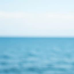 Hand holding house model with heart and keys against a sea background. Concept for real estate, home loan, love home, and property investment.