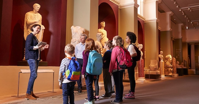 Alunni e insegnanti in gita scolastica al museo con una guida. (Adobe Stock)