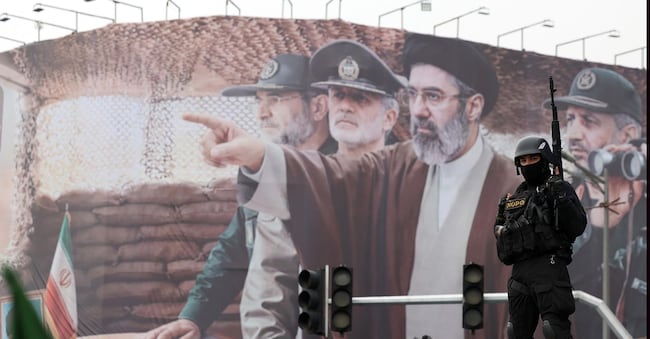 Un membro delle forze di sicurezza iraniane monta la guardia davanti a un cartellone pubblicitario che raffigura il leader supremo iraniano Mojtaba Khamenei e alcuni comandanti militari iraniani durante una manifestazione per celebrare la Giornata internazionale di Quds a Teheran, in Iran, il 13 marzo 2026. Istituita nel 1979, la Giornata di Quds si celebra ogni anno l'ultimo venerdì del Ramadan per esprimere solidarietà al popolo palestinese e protestare contro il controllo israeliano su Gerusalemme. La celebrazione di quest'anno si svolge mentre un'operazione militare congiunta tra Stati Uniti e Israele, avviata il 28 febbraio, continua a colpire siti strategici in tutto l'Iran. EPA/ABEDIN TAHERKENAREH