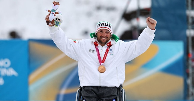 Paralimpiadi Milano Cortina 2026 - Sci di fondo paralimpico - Cerimonia di premiazione della gara maschile di sci di fondo 20 km con partenza a intervalli (categoria seduti) - Stadio di sci di fondo di Tesero, Lago, Italia - 15 marzo 2026. Il medaglia di bronzo Giuseppe Romele (Italia) festeggia sul podio durante la cerimonia di premiazione della gara maschile di sci di fondo 20 km con partenza a intervalli (categoria seduti) REUTERS/Sarah Meyssonnier