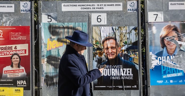 Un uomo cammina davanti a manifesti elettorali a Parigi (foto Epa)