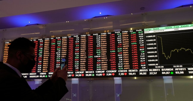 Un uomo scatta delle foto ai monitor delle quotazioni azionarie alla Borsa B3 di San Paolo, in Brasile.  (AP Photo/Andre Penner)