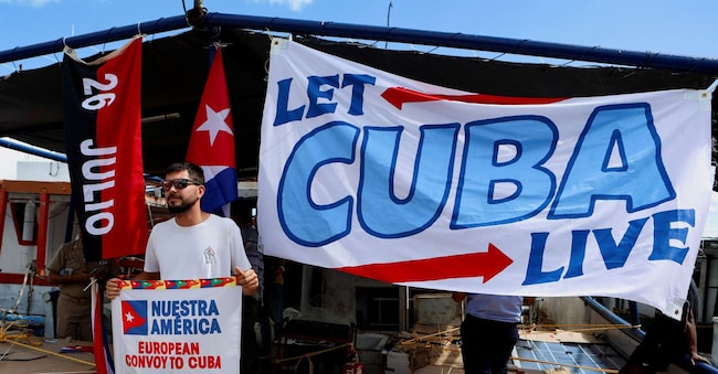 Un attivista che partecipa alla flottiglia del "Nuestra America Convoy" tiene in mano un cartello su una barca mentre attende di salpare alla volta di Cuba con beni di prima necessità, nel porto di Yucalpeten a Progreso, nello Stato dello Yucatan, in Messico, il 20 marzo 2026. REUTERS/Lorenzo Hernandez REUTERS
