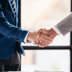 Two men shake hands in a business meeting. Scene is professional and formal. The handshake symbolizes agreement and trust between the two men Freedomz - stock.adobe.com