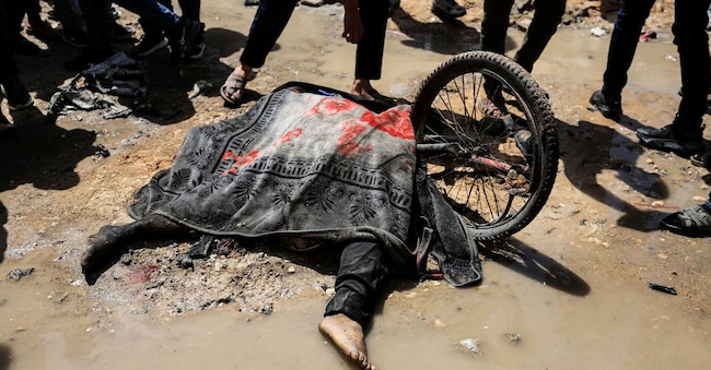 Palestinesi si radunano attorno a un corpo di una persona colpita da un attacco israeliano mentre andava in bicicletta. REUTERS/Dawoud Abu Alkas REUTERS