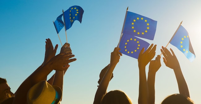People with raised hands waving flags of the European Union. European dream. Future of Europe. European flag. Fans from Europe rooting for their team. DenisProduction.com - stock.adobe.com