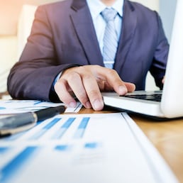 Working process startup. Businessman working with new finance project at office with laptop, tablet and graph data documents on his desk