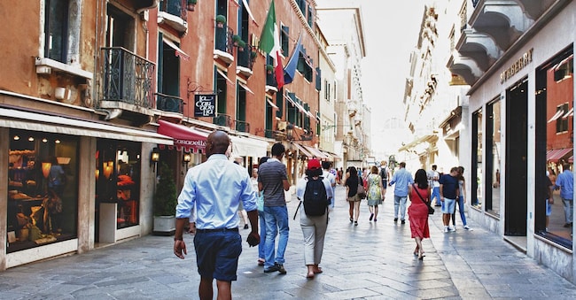Alcuni passanti percorrono una delle principali vie dello shopping a Venezia, in Italia.  (Fotografo: Marco Secchi/Bloomberg)