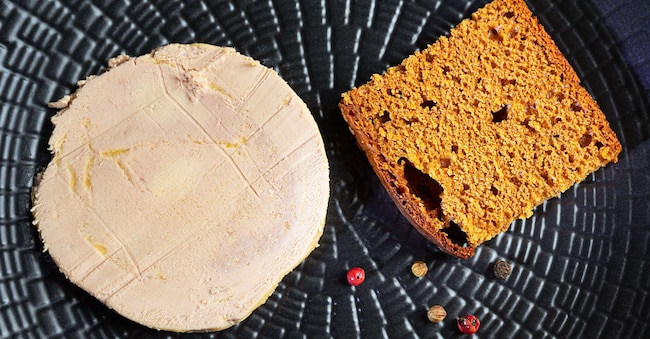 Foie gras, pan di zenzero e grani di pepe su un piatto nero Alamy Stock Photo