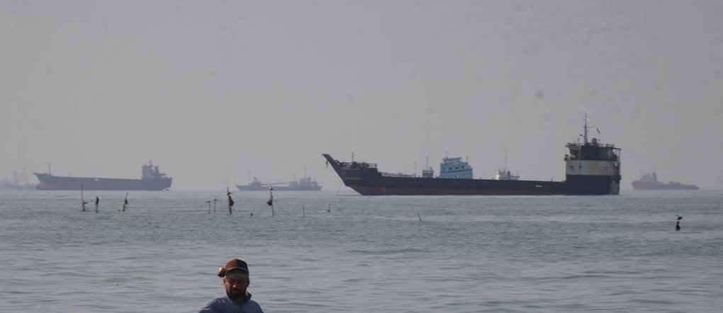 Un uomo è in piedi nell'acqua, apparentemente intento a pescare, mentre navi portarinfuse, navi da carico e imbarcazioni di servizio si stagliano all'orizzonte nello Stretto di Hormuz al largo di Bandar Abbas, in Iran, lunedì 27 aprile 2026. (Razieh Poudat/ISNA via AP)      Associated Press/ LaPresse Solo Italia e Spagna APN