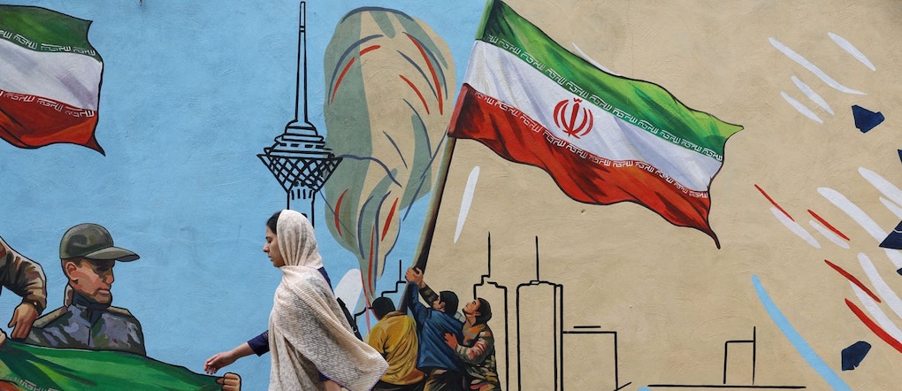 Una donna iraniana cammina accanto a un murale in una strada di Teheran, in Iran, il 5 maggio 2026. Majid Asgaripour/WANA (West Asia News Agency) via REUTERS