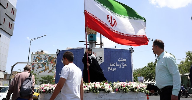 Una donna sventola la bandiera nazionale iraniana in una strada di Teheran, Iran, il 17 maggio 2026. Il conflitto tra Iran e Stati Uniti continua, con il presidente americano Donald Trump che ha ripetuto le minacce di una nuova azione militare EPA/ABEDIN TAHERKENAREH EPA