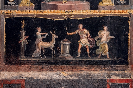 Casa dei Vettii. Scena sacrificale in cui una cerva va verso l’altare; a sinistra, una colonna con la statua di Artemide: in tutte le culture arcaiche del Mediterraneo l’uccisione di un animale a scopo alimentare era legata ad attività rituali Tutte le immagini del Parco Archeologico di Pompei sono su concessione del Ministero della Cultura