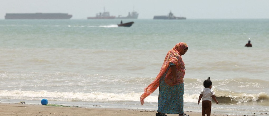 Una madre con bambino passeggia sulla spiaggia di Bandar Abbas, in Iran, davanti allo Stretto di Hormuz via REUTERS