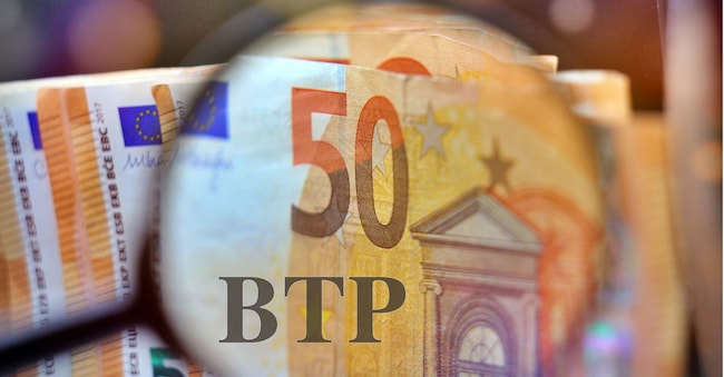 Magnifying glass over the pile of money with the text “BTP” translating as Italian government bonds. RafMaster - stock.adobe.com