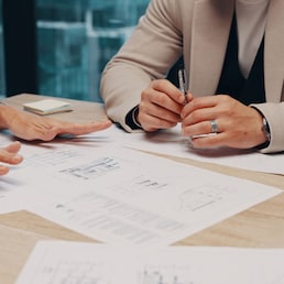 Business people, hands or meeting with documents for architecture project, design or layout. Group, building designers or discussion with construction paperwork for floor plan or remodeling in office. ChasingMagic25/peopleimages.com - stock.adobe.com