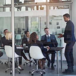 Executive, meeting and group in office room for corporate planning, strategy or business training. Management, people at table and businessman or speaker, mentor and professional advice to company. Cecilie Arcurs/peopleimages.com - stock.adobe.com