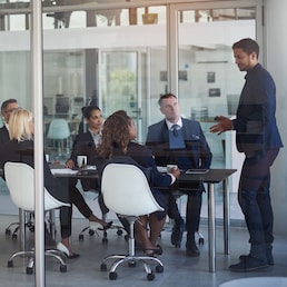 Executive, meeting and group in office room for corporate planning, strategy or business training. Management, people at table and businessman or speaker, mentor and professional advice to company. Cecilie Arcurs/peopleimages.com - stock.adobe.com