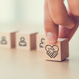 Empathy in leadership concept. Wooden block symbolizing empathy and partnership among blocks representing individuals, emotional intelligence and trust in workplace leadership and team collaboration. Parradee - stock.adobe.com